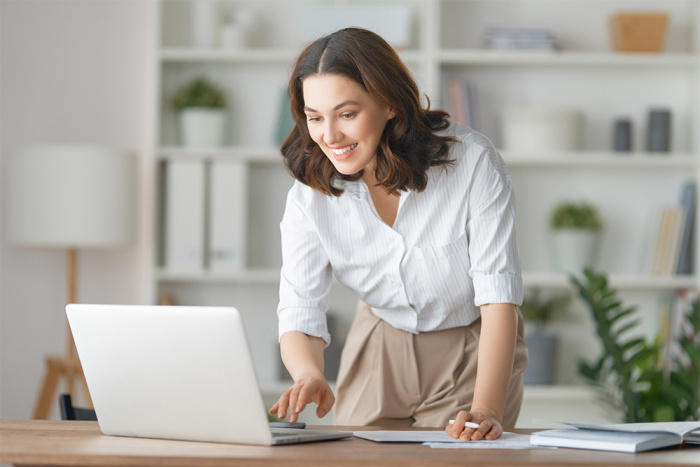 A woman is happily surprised after reading about credit union checking account benefits online.