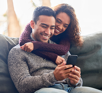 Smiling couple looking at phone at APGFCU High Yield Checking Account