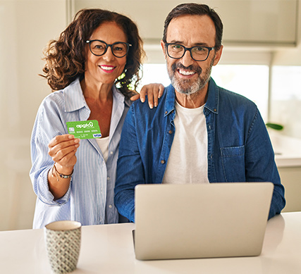 Couple sitting at laptop holding an APGFCU Visa Cash Back Credit Card